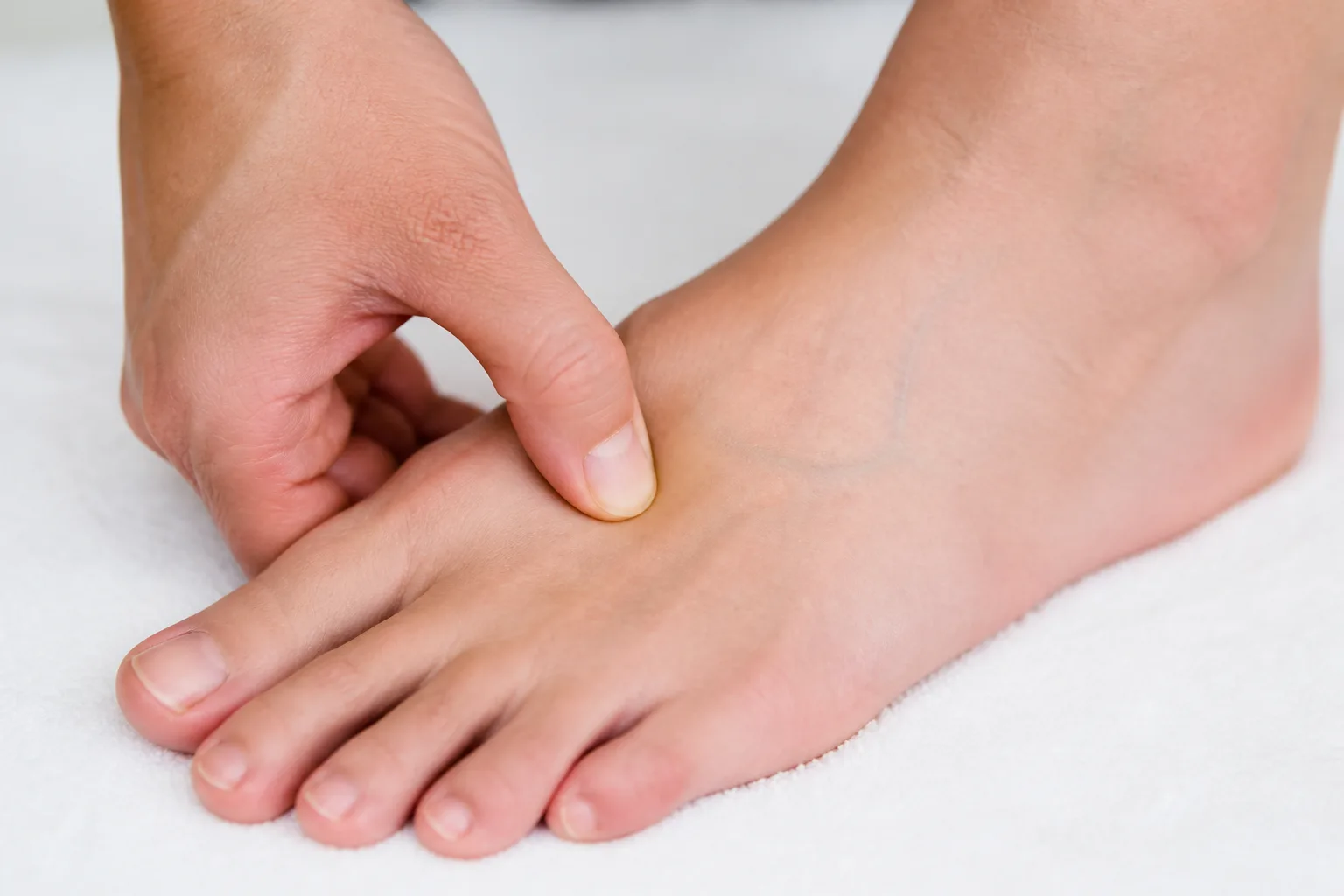 Thumb pressing Tai Chong LR3 on the top of the foot