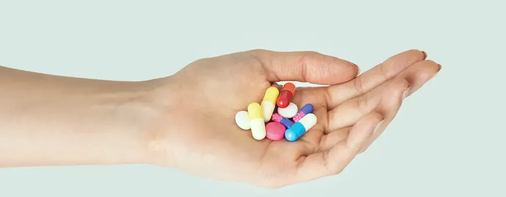 Hand holding assorted supplement capsules during cancer nutrition decisions