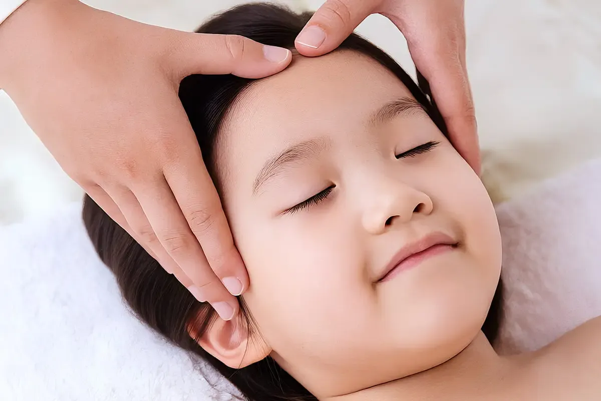 Gentle paediatric Tuina on a child's head and face for school-season calm
